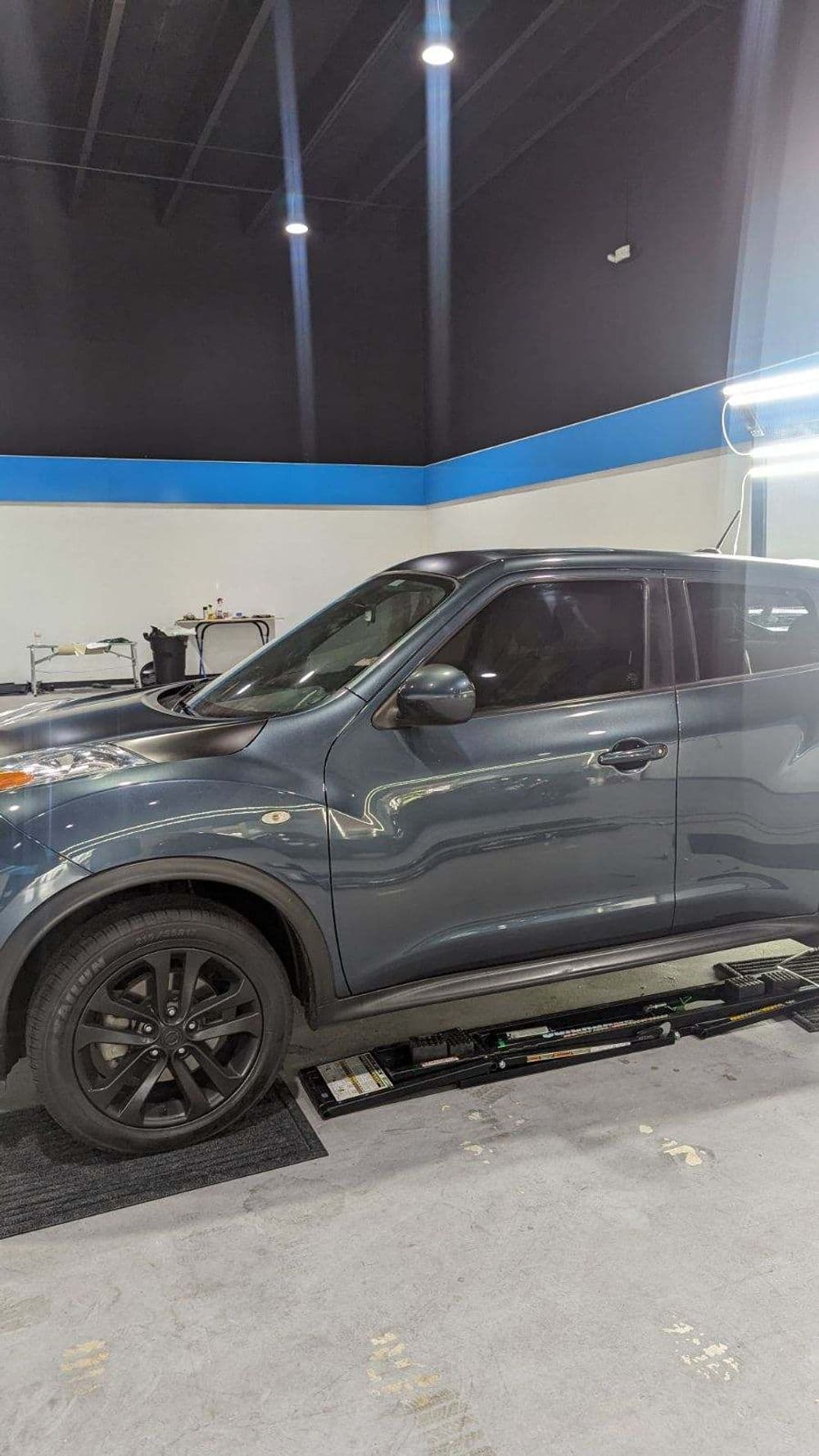 Gray compact car with black rims in a modern automotive service center.