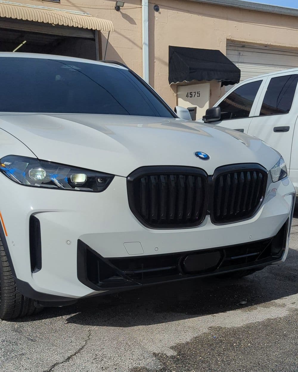Front view of a white BMW X7 with distinctive kidney grille and modern headlights.