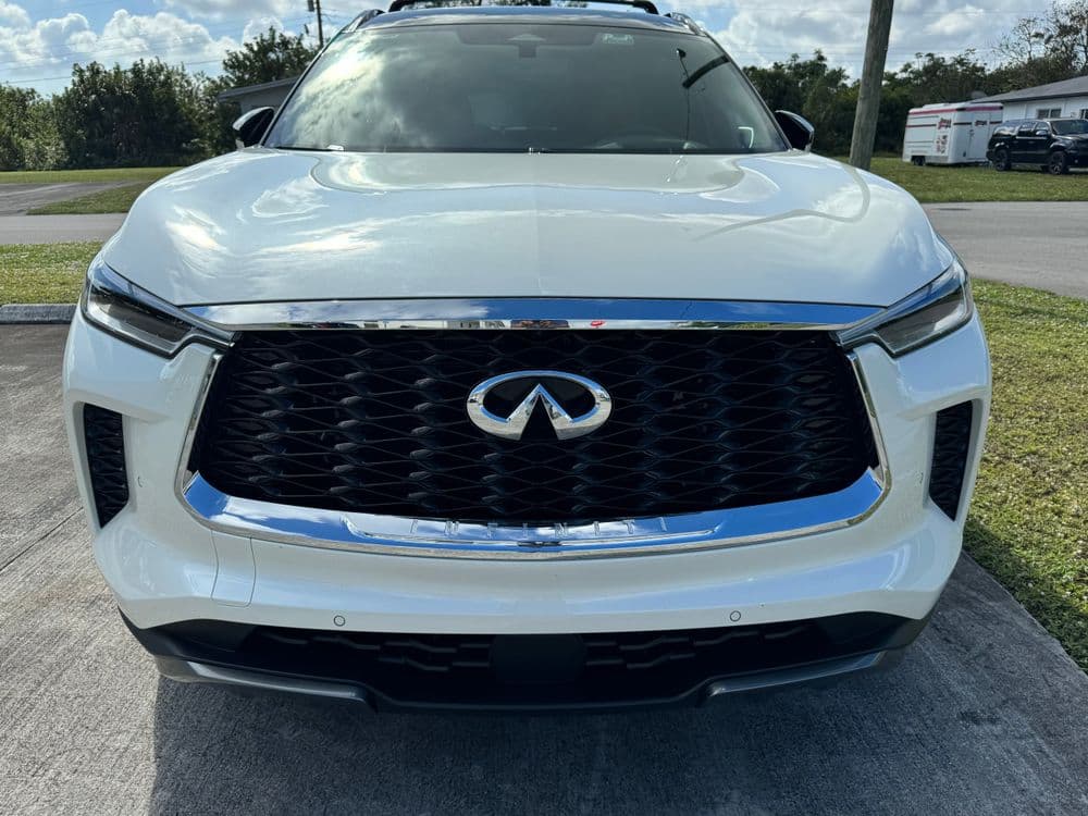 Front view of a white Infiniti QX60 SUV showcasing its sleek design and distinctive grille.
