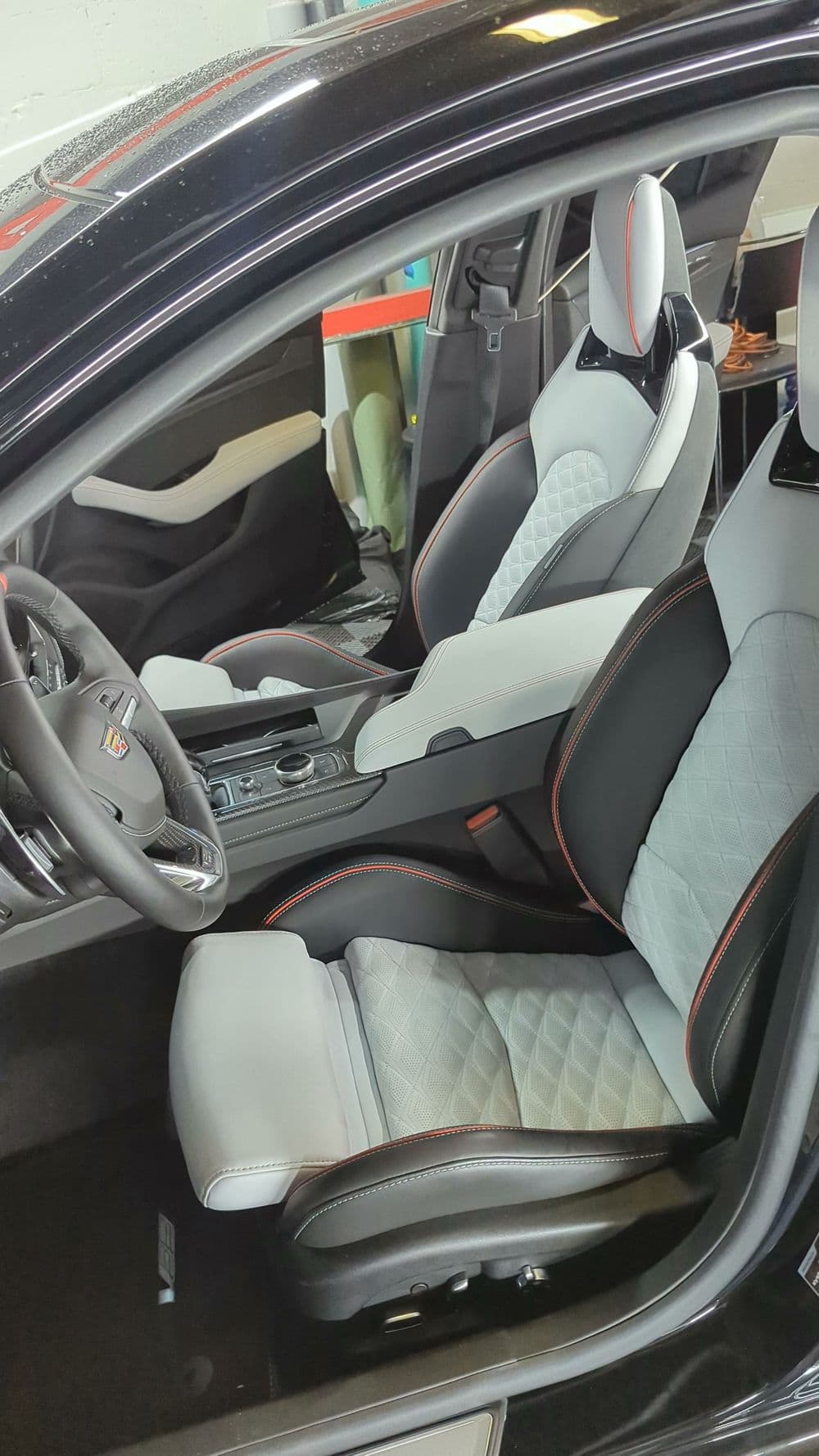 Luxury Porsche car interior featuring sporty gray and black seats with red accents.