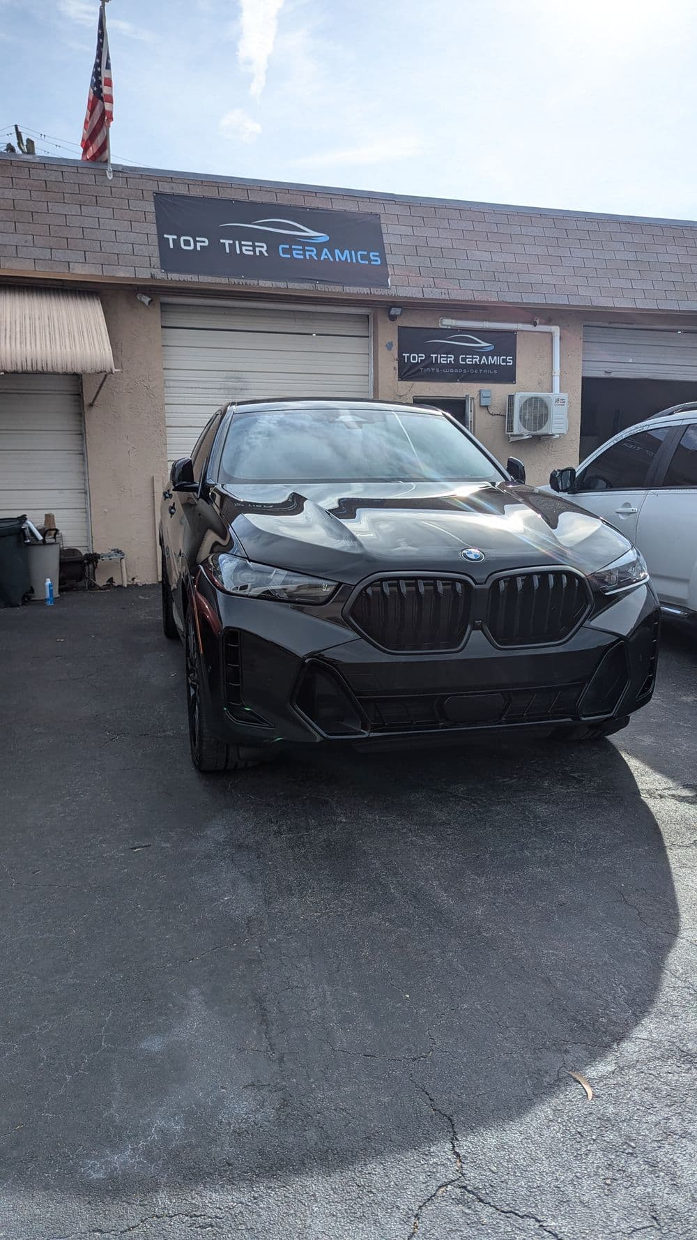 Black BMW parked outside Top Tier Ceramics, showcasing sleek design and modern features.