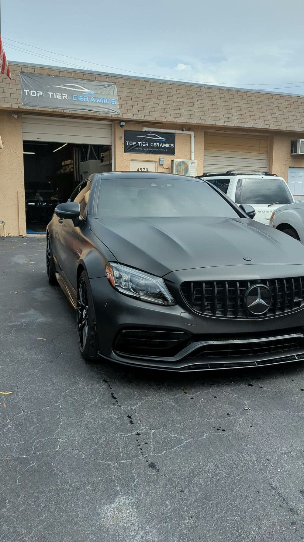 Matte black Mercedes parked outside Top Tier Ceramics, showcasing a sleek, modern design.