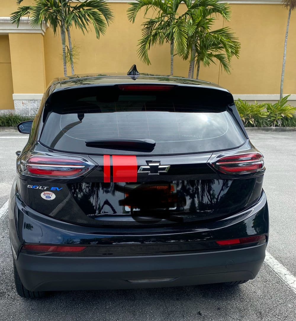 Black Chevrolet Bolt EV parked in a sunny location with palm trees in the background.