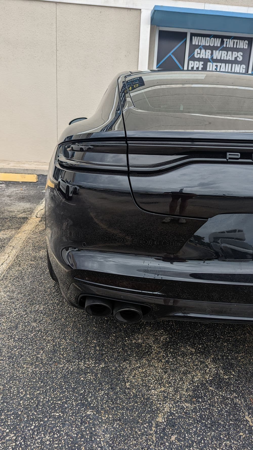 Black sports car rear view showcasing sleek design and dual exhaust tips.