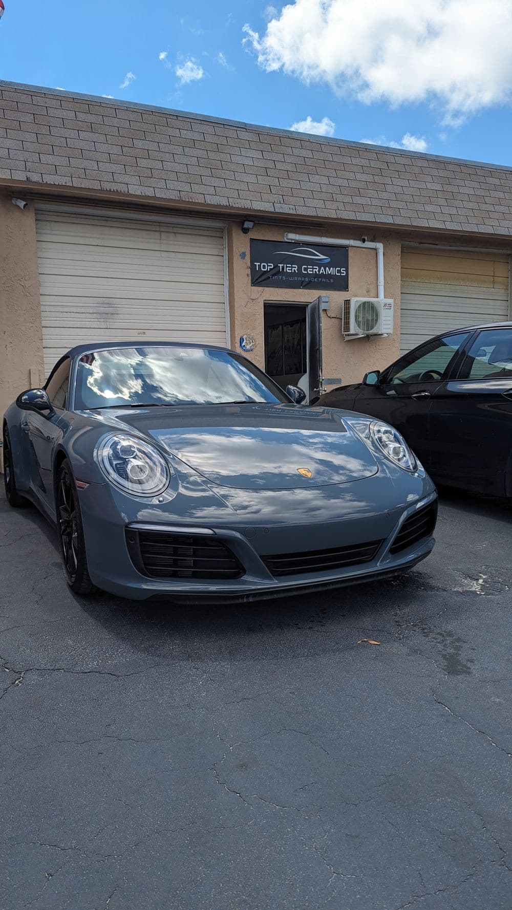 Porsche 911 Carrera S parked outside Top Tier Ceramics with blue sky background.