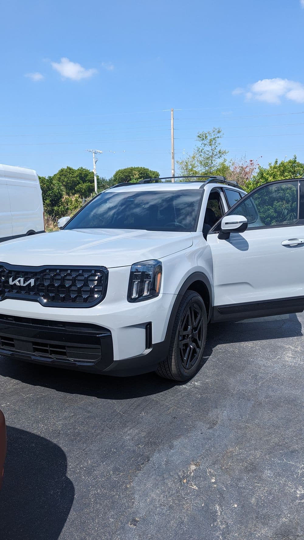 White Kia SUV parked with doors open, showcasing modern design and sporty features.