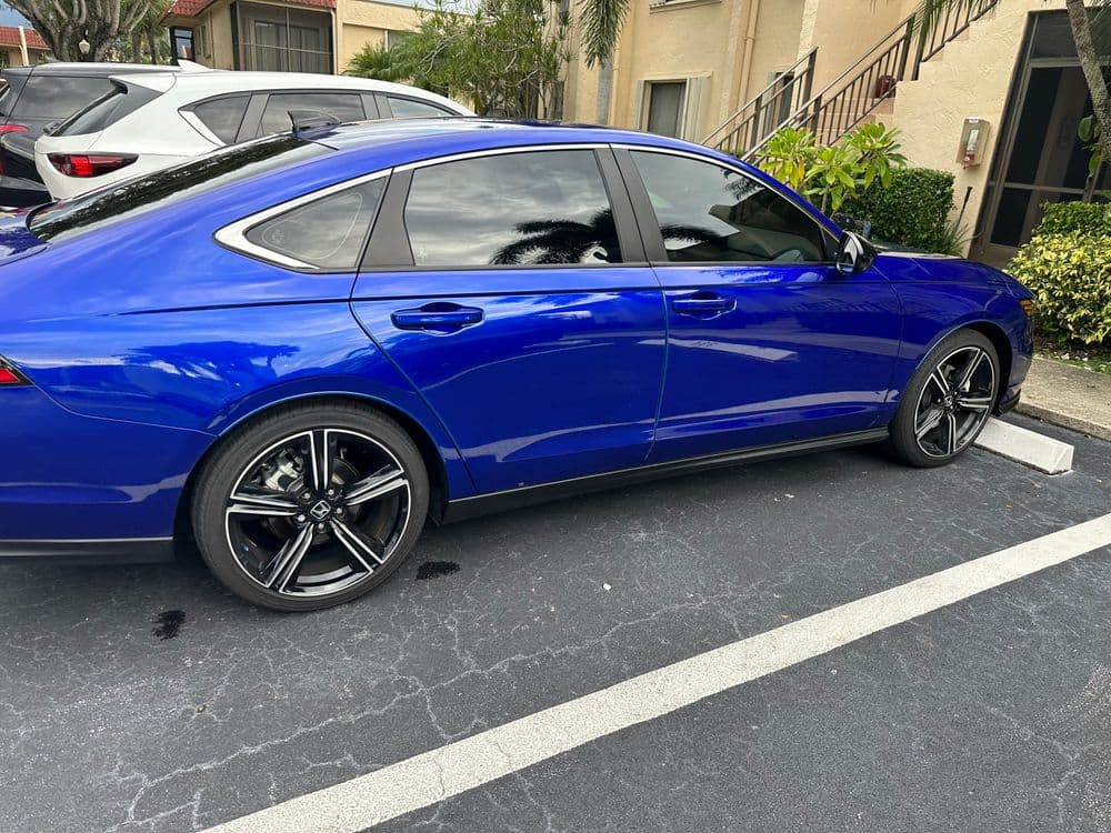 Blue sedan parked in a lot, featuring sleek design and black alloy wheels.