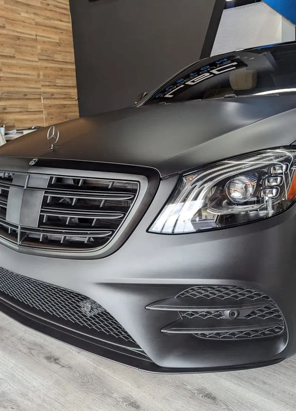 Sleek black matte Mercedes-Benz S-Class luxury sedan in modern showroom setting.
