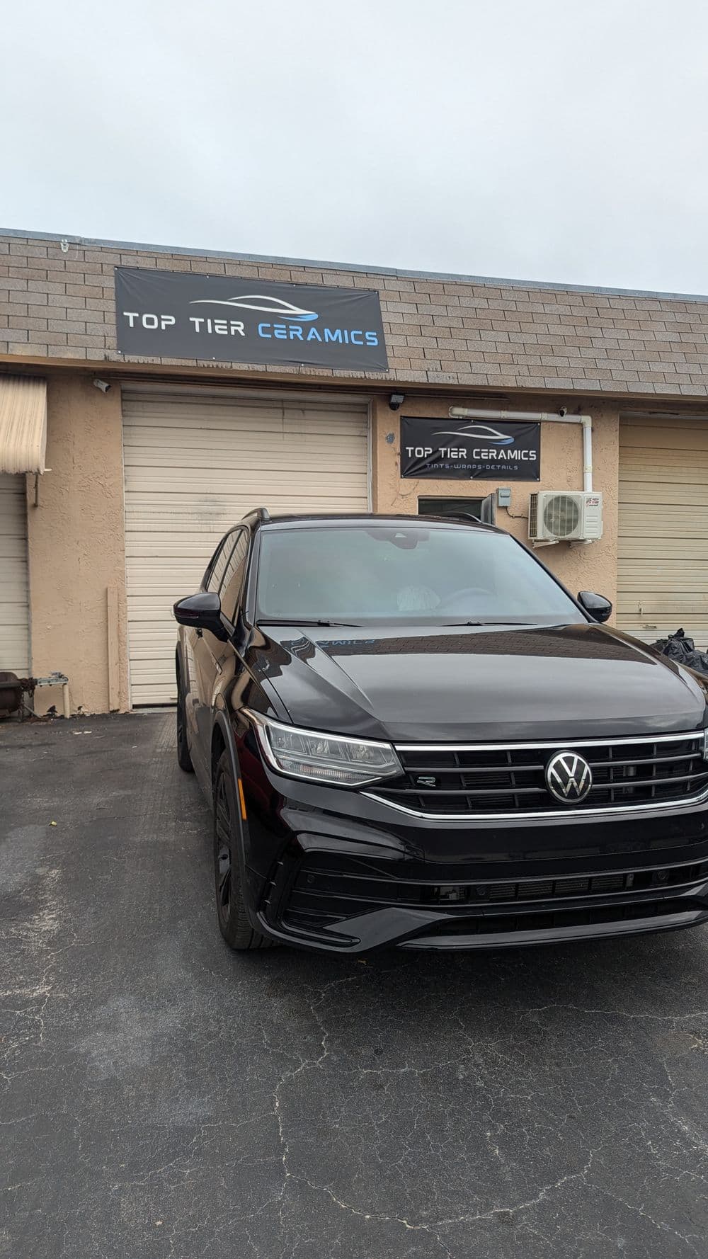 Black Volkswagen SUV parked in front of Top Tier Ceramics shop.