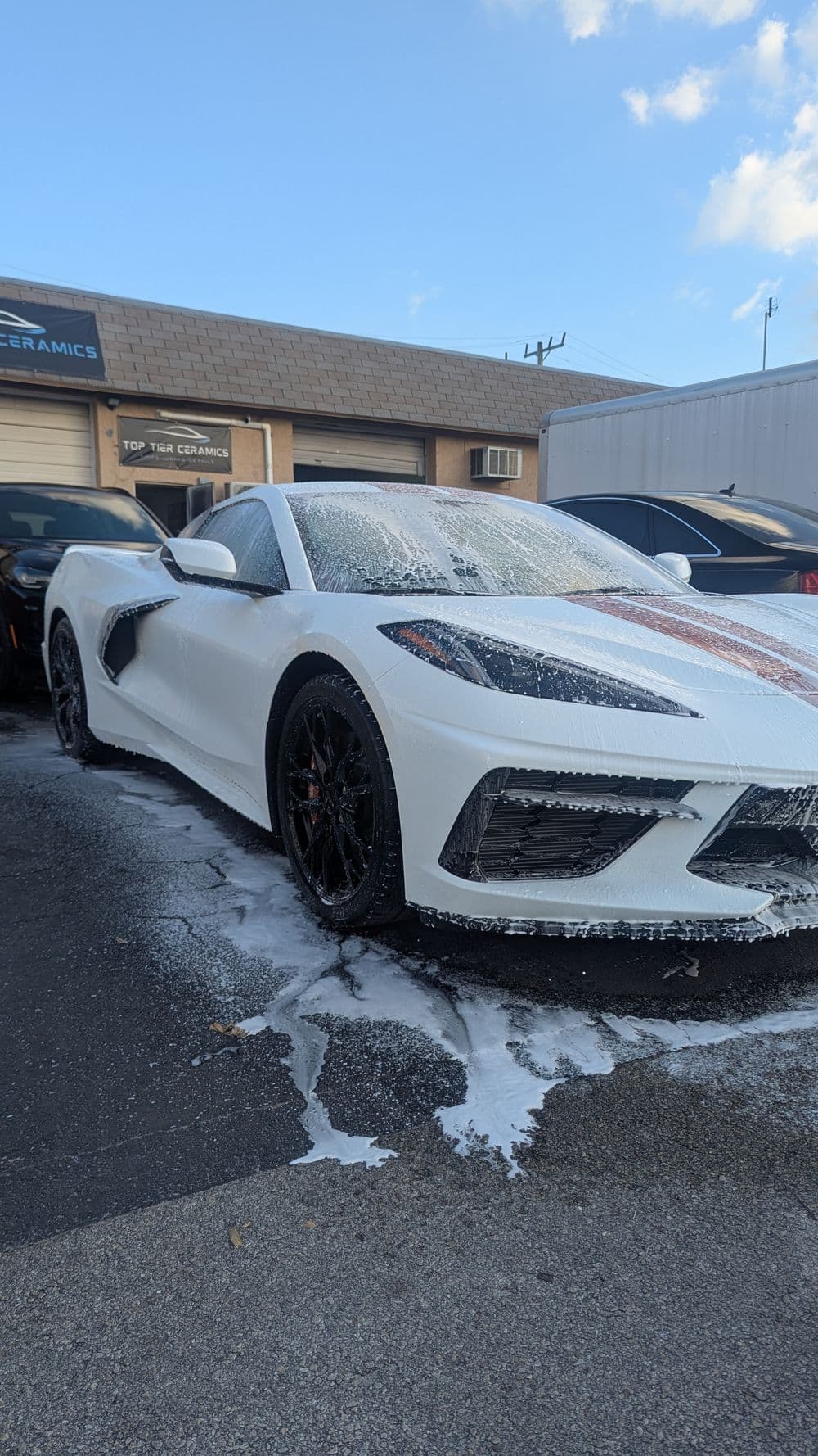 White Corvette C8 covered in foam during a car wash outside Top Tier Ceramics.